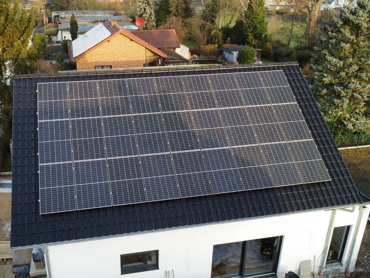 Weißes Einfamilienhaus in Düren, dessen Satteldach fast vollständig mit schwarzen Solarmodulen belegt ist, von oben gesehen