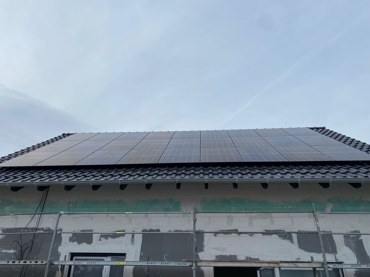 Solarmodule auf dem Ziegeldach eines Neubaus in Düren, dessen Fassade noch unverputzt und eingerüstet ist